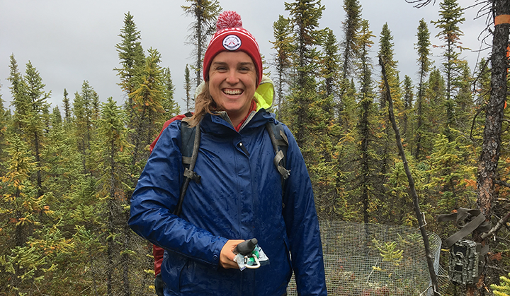 PhD student Kirsten Reid standing outdoors smiling on a forested background