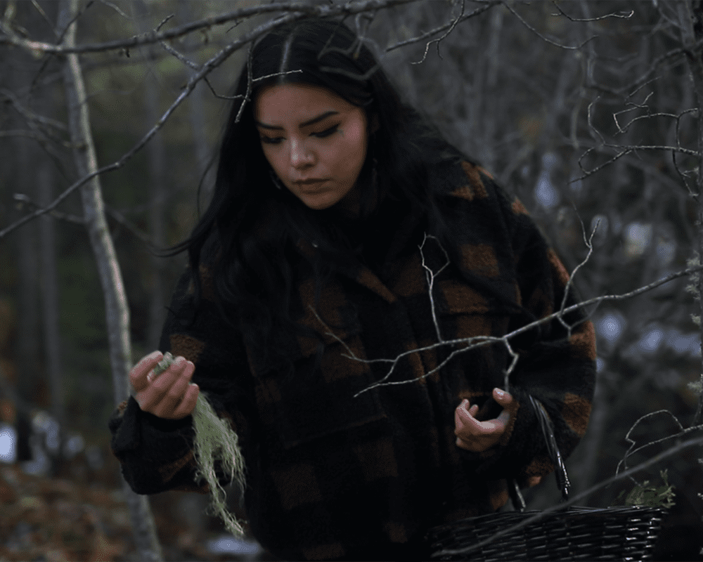 A woman gathers lichen in the forest to make soap out of