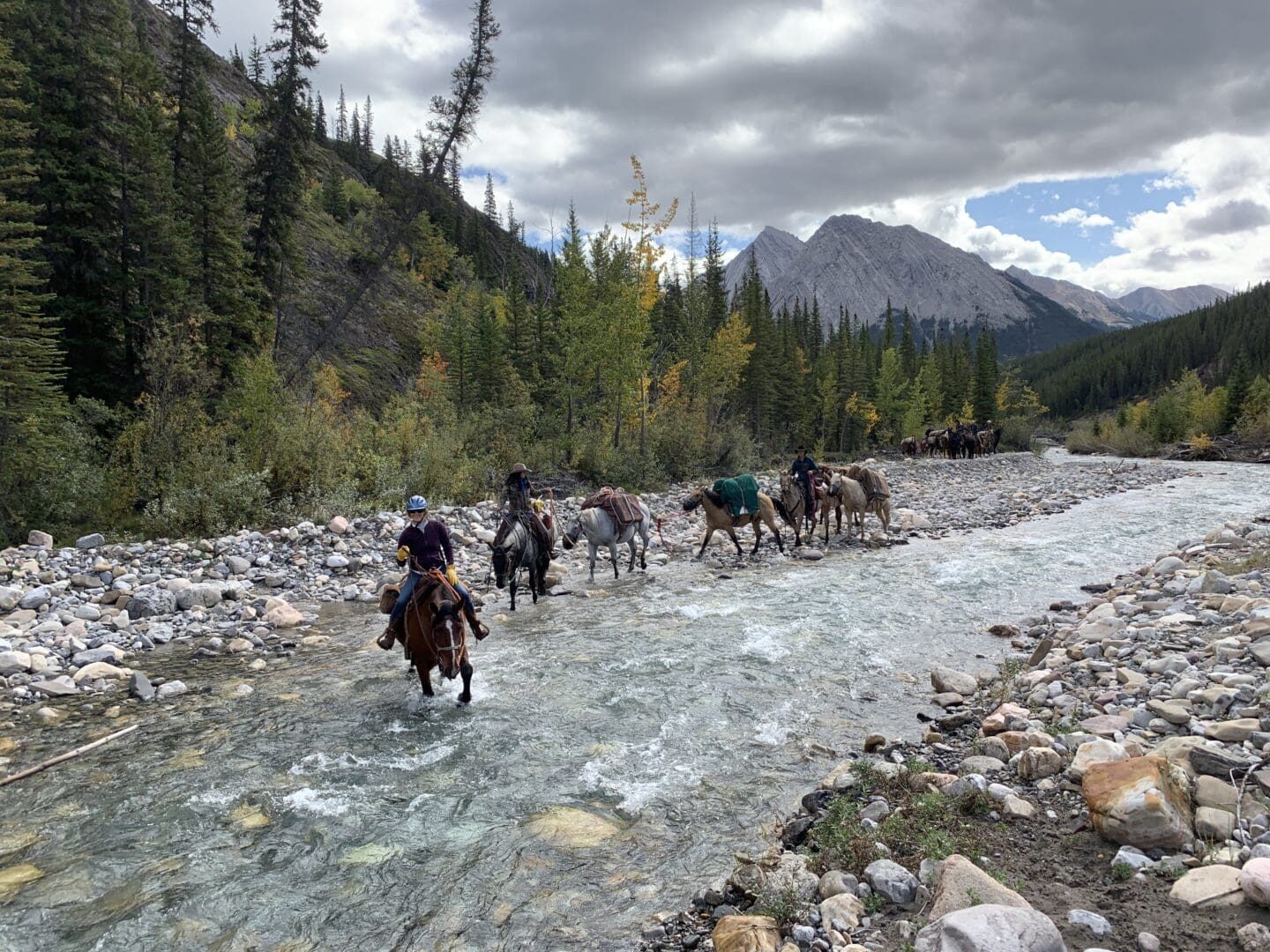 People on horses ford a river