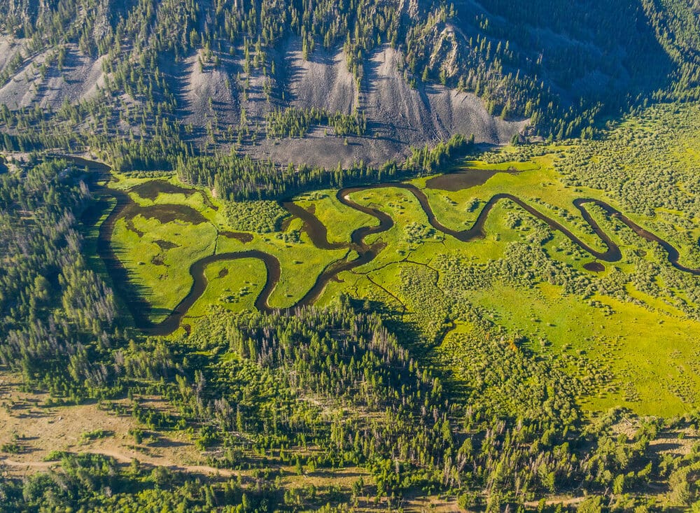An aerial photo of a green landscape with a snaking river through it