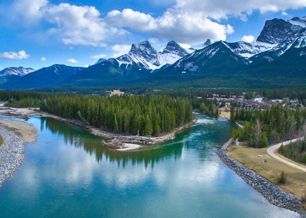 View of the Bow River in Canmore, Alberta and the Three Sisters mountains in the spring or summer. Shutterstock photo.