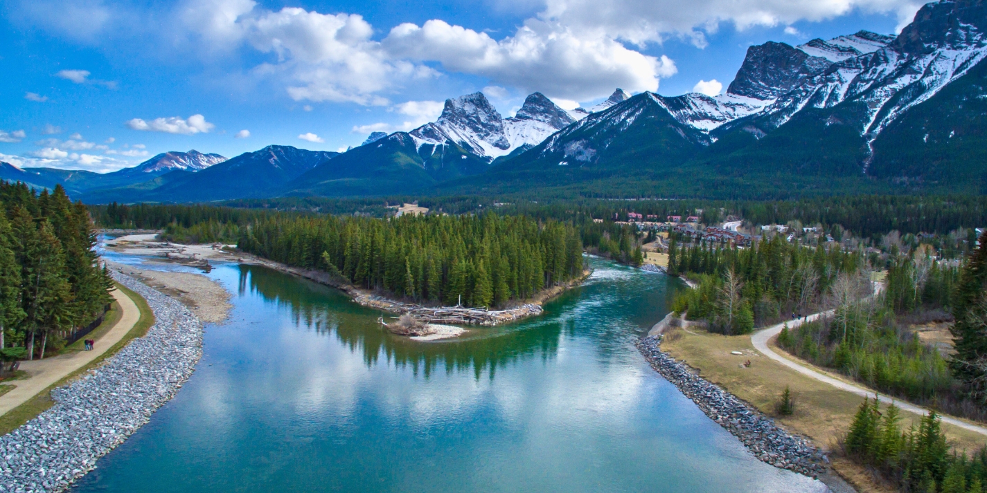 View of the Bow River in Canmore, Alberta and the Three Sisters mountains in the spring or summer. Shutterstock photo.