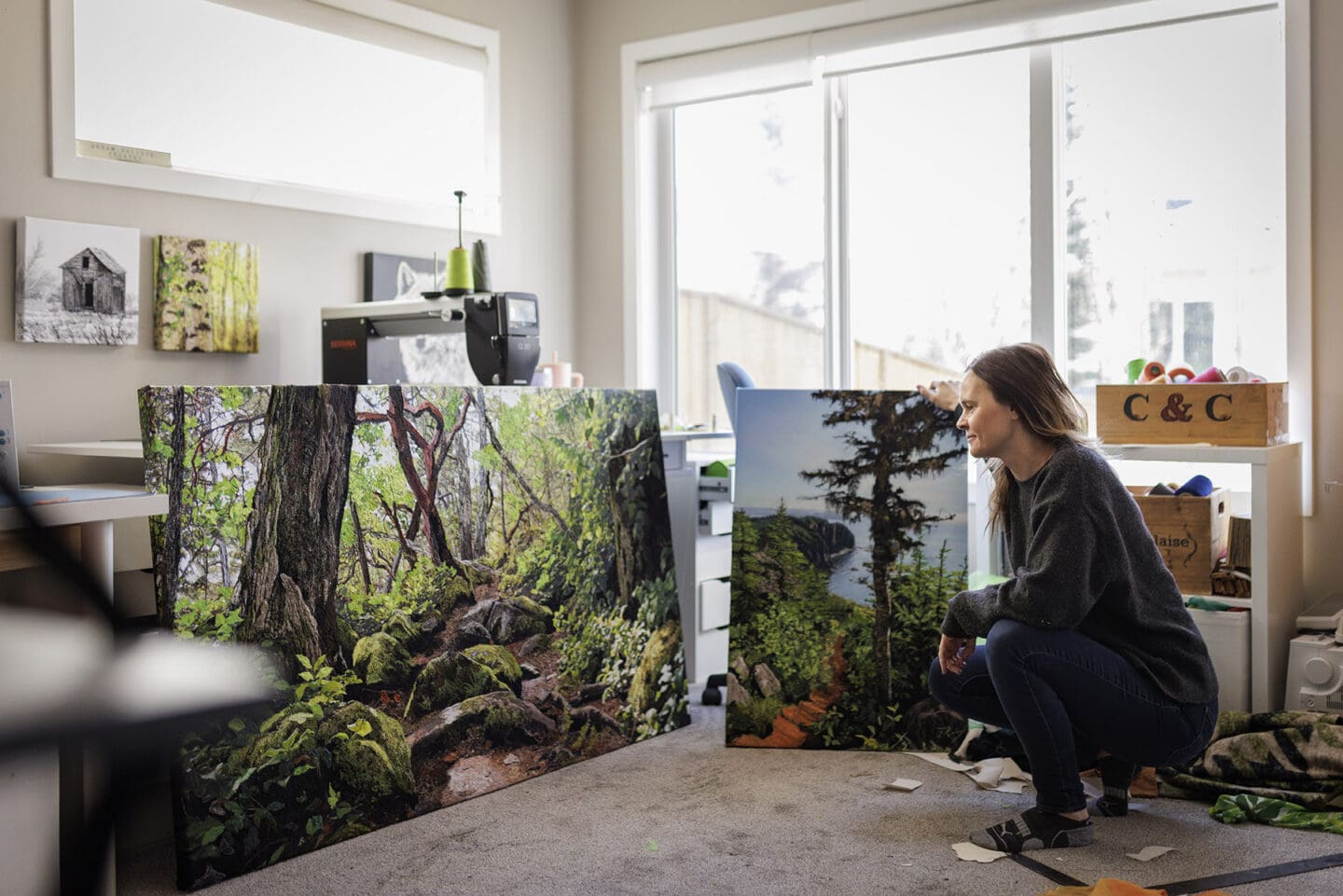 Artist Alison King squats in front of her art in her study